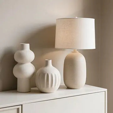 Stylish home decor accessories including ceramic vases, table lamps, and decorative items arranged on modern interior background