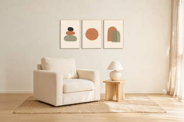 Three framed abstract nursery prints in terracotta and sage hung in a row on a warm white wall