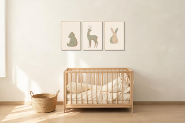 Three framed woodland animal nursery prints hung in a row above a light oak crib